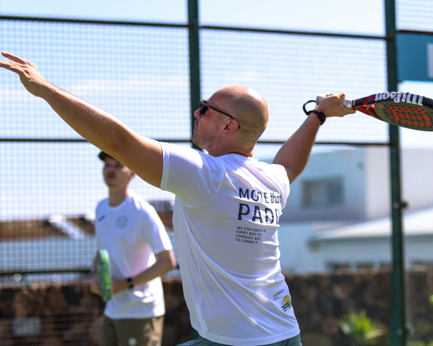 Teilnehmer übt den Trainingsschlag mit dem Coach auf dem Padelplatz
